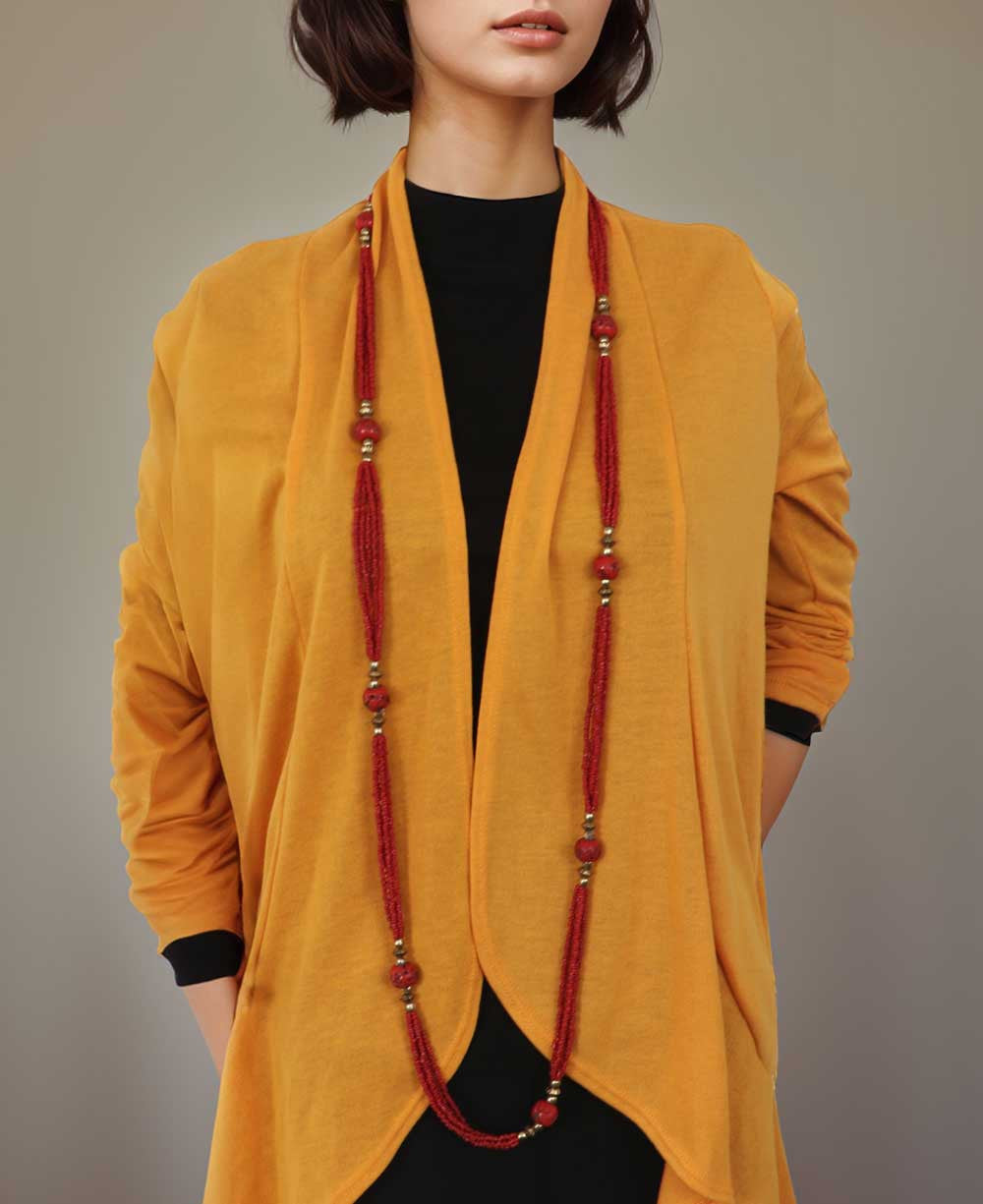 A long red beaded rope necklace worn doubled