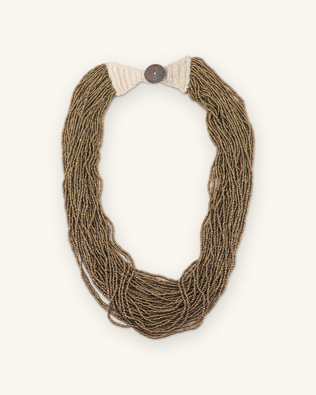 Antique gold seed bead necklace laid flat, showing the cream crochet end panels and button closure, shown on a sand background