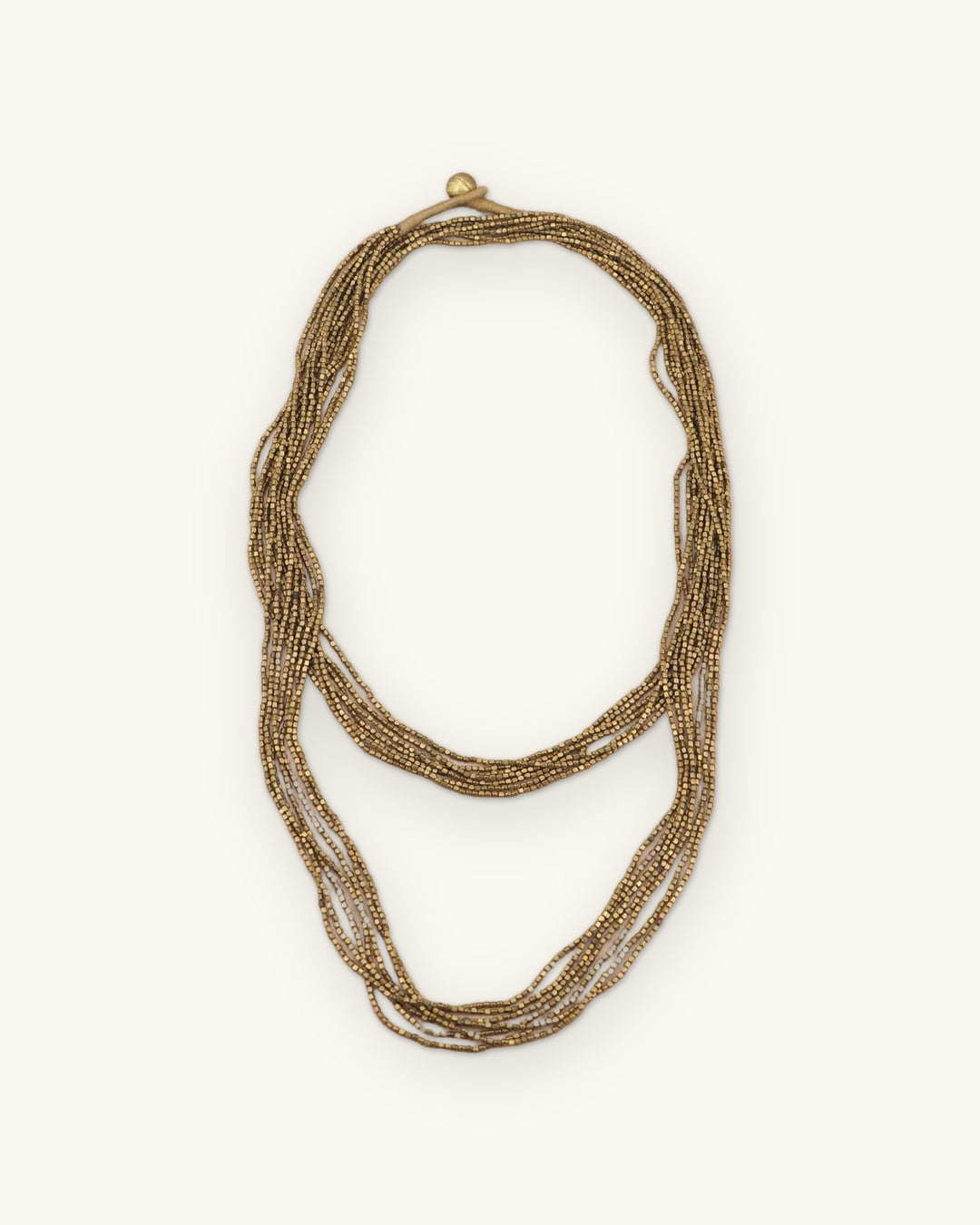 Antique gold multi-strand glass bead necklace, Tibetan beadwork made in Nepal and India, doubled into two loops, shown on a sand background