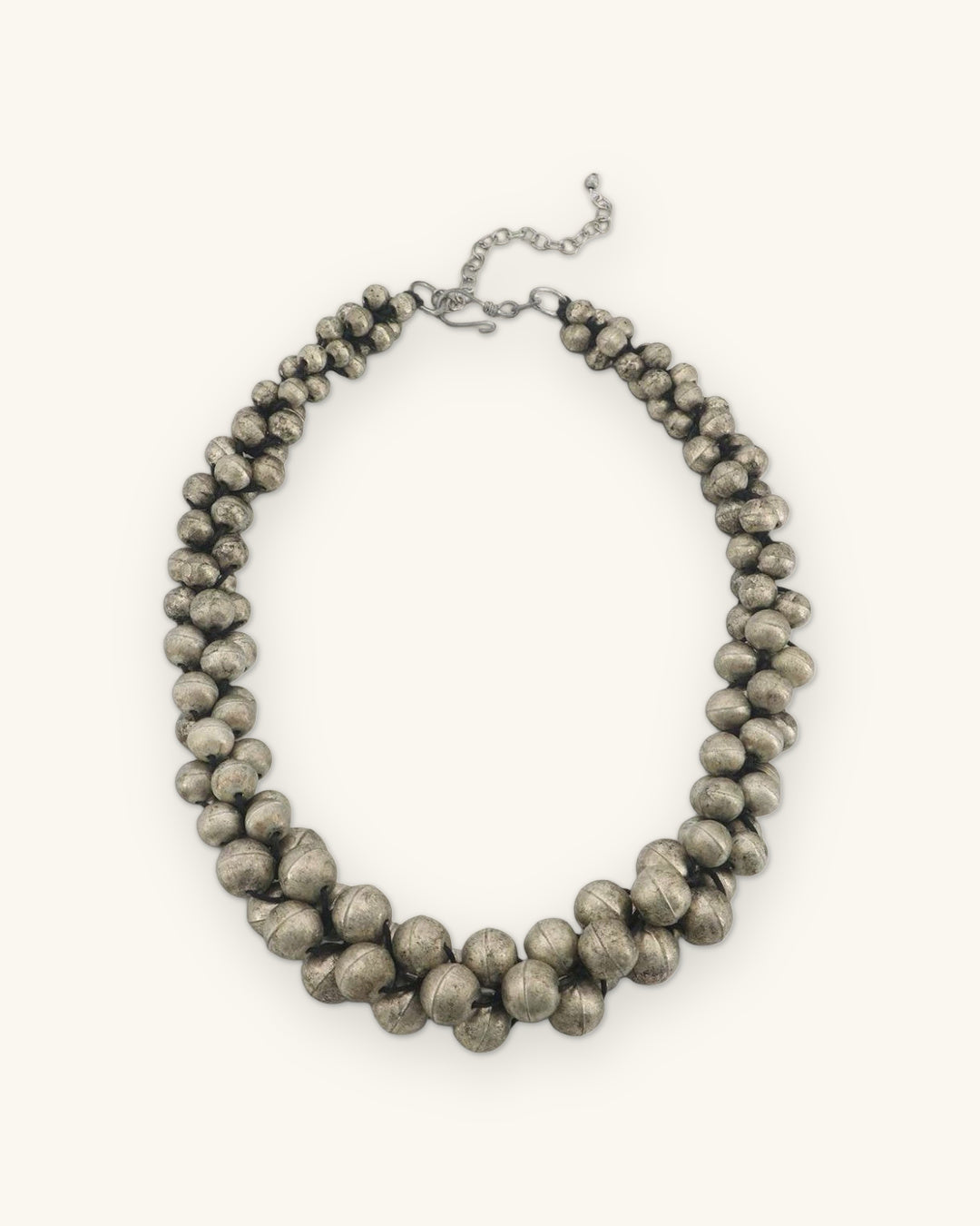 Antique silver-tone twisted bead collar necklace laid flat with lobster clasp and extender chain, shown on a sand background