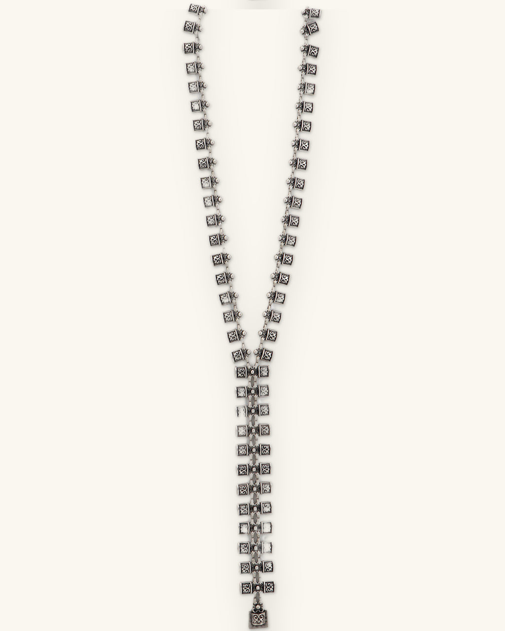 Scroll-stamped square link Y-necklace laid straight to show the long center drop, shown on a sand background