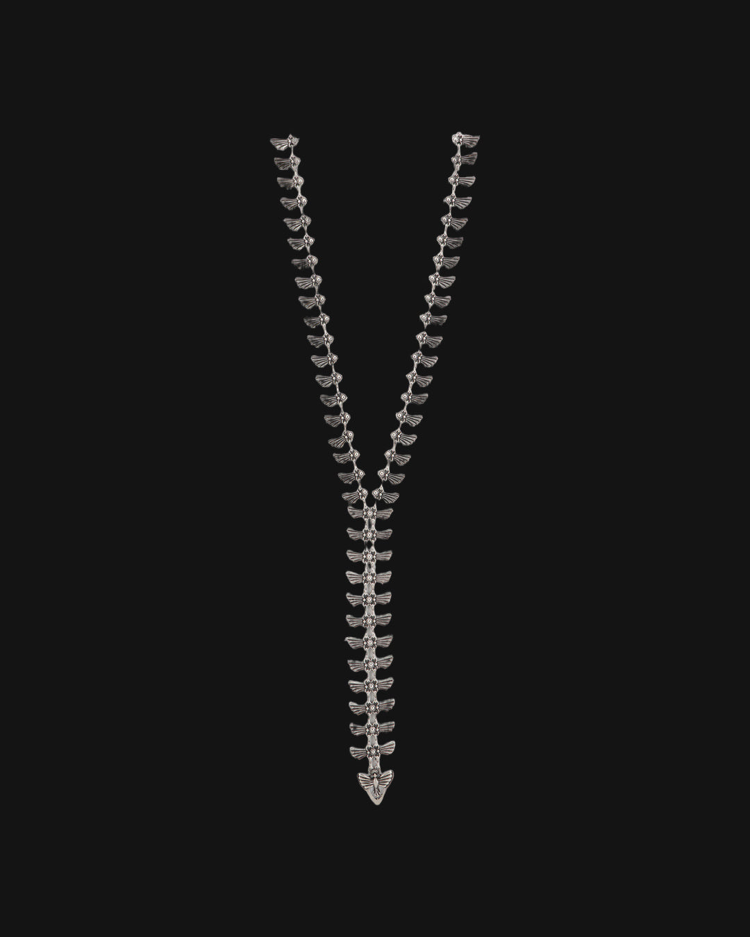 Winged-tab silver Y-necklace laid straight with a winged charm at the end of the drop, shown on a black background