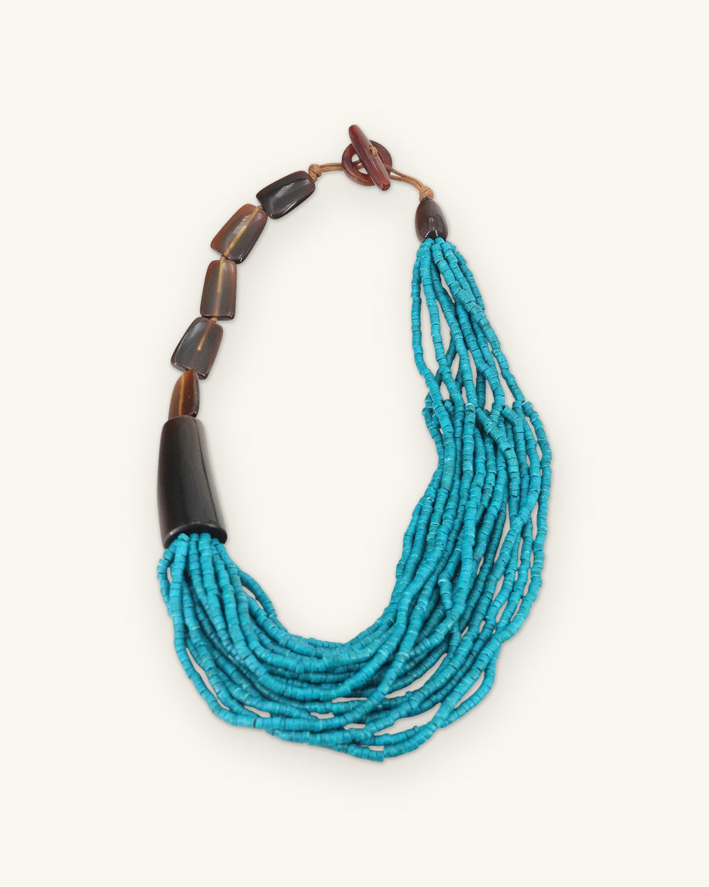 Turquoise coconut bead necklace with brown horn segments, dark horn cone and toggle closure, laid flat, shown on a sand background