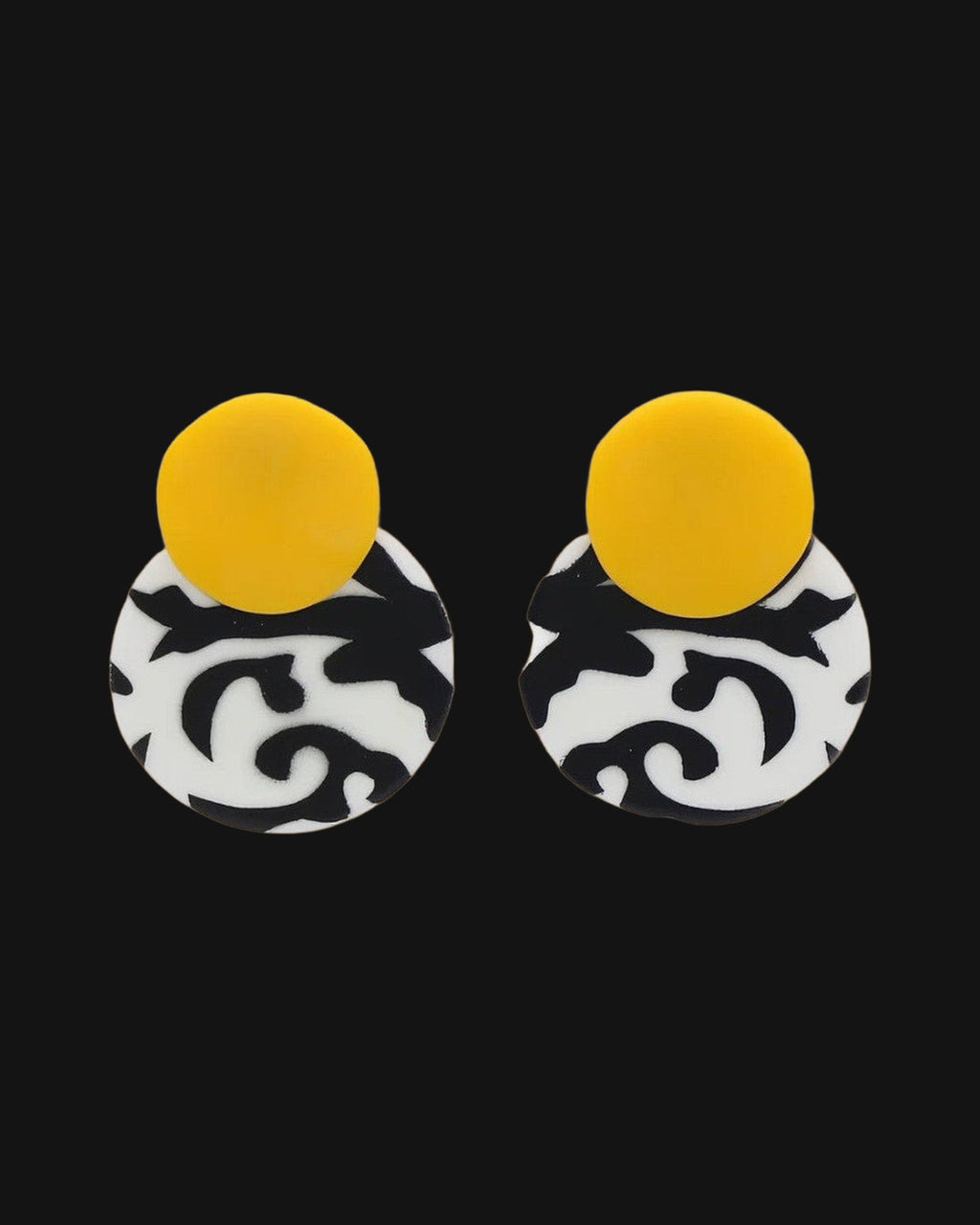Double-disc drop earrings with a yellow top disc over a black and white swirl disc, hand-painted resin from the Philippines, shown on a black background
