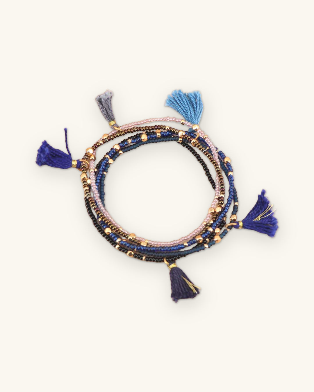 Set of five beaded stretch bracelets in blues with cotton tassels and gold-tone accents, Guatemalan beadwork, shown on a sand background