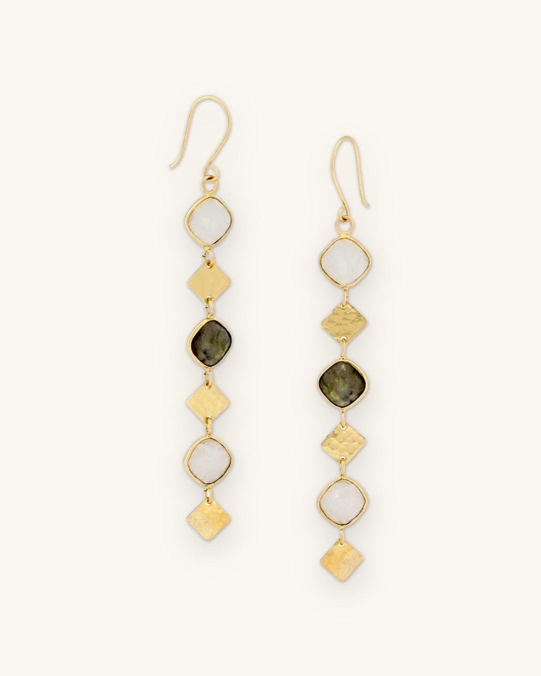 Segmented drop earrings with labradorite and moonstone set in hammered brass, made in India, shown on a sand background