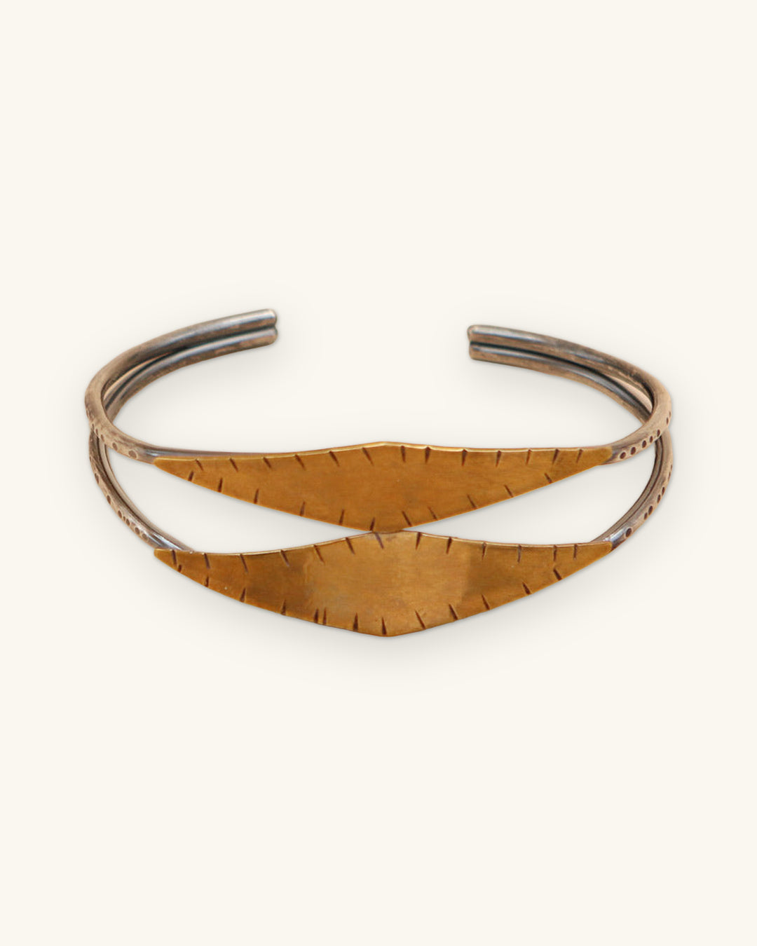 Medina cuff bracelet of oxidized sterling silver bands and hammered brass leaves, hand-cut in the USA, shown on a sand background
