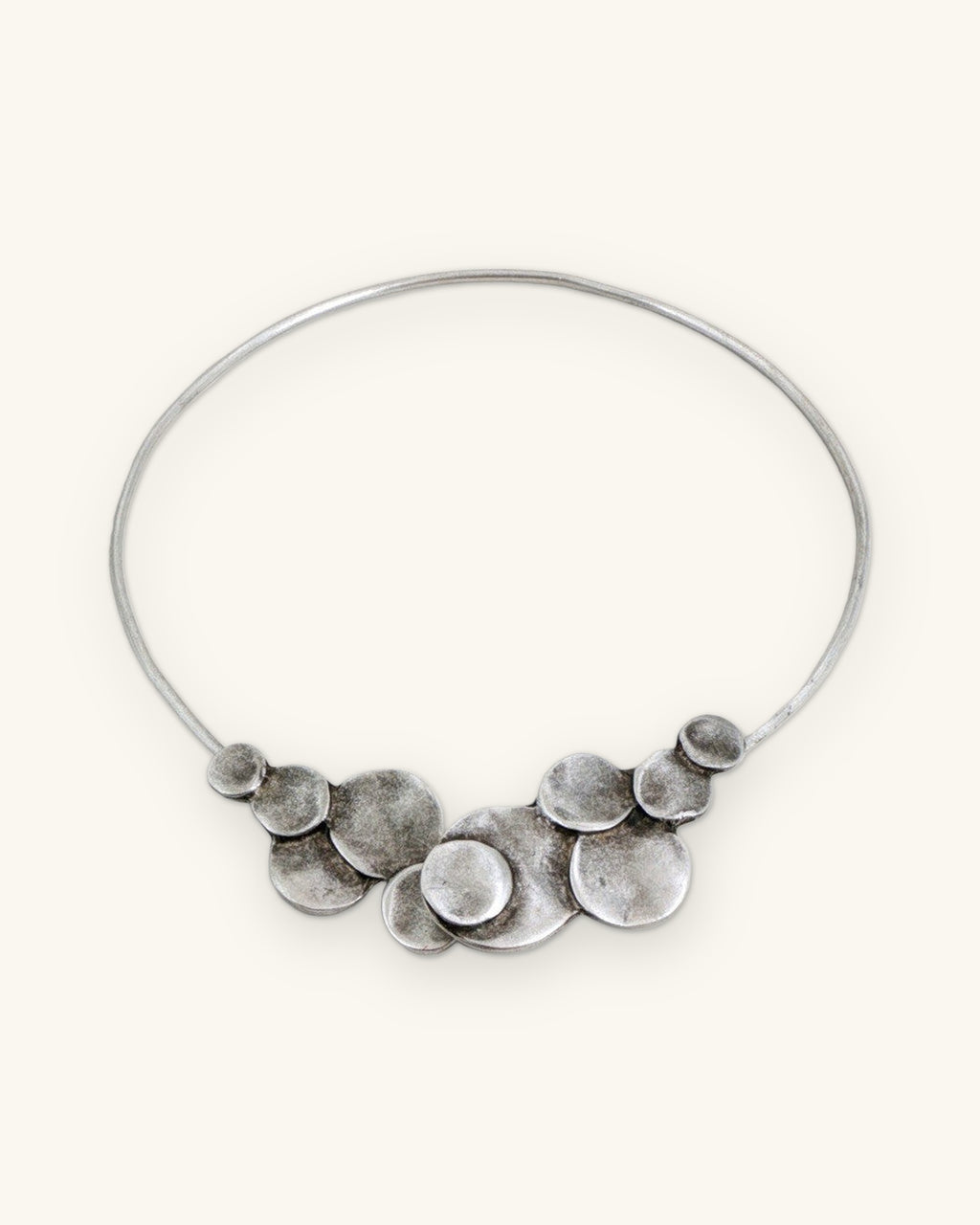 Silver-tone disc cluster collar with the ends closed so the discs form one row at the front, shown on a sand background