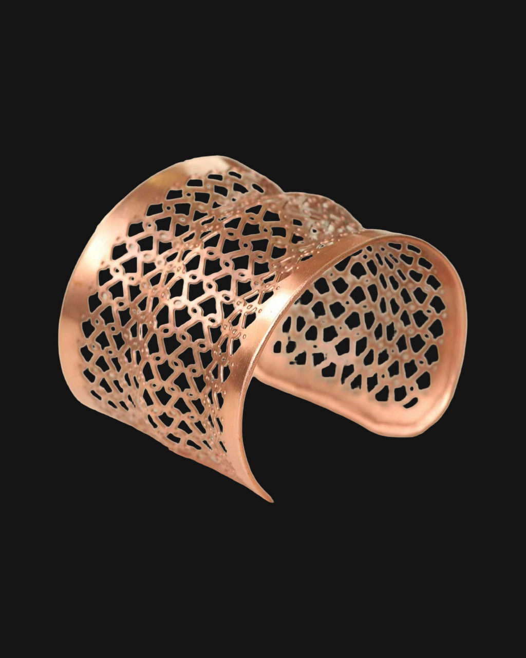 Pierced copper lattice wide cuff bracelet with a geometric cutout pattern, handmade in India, shown on a black background