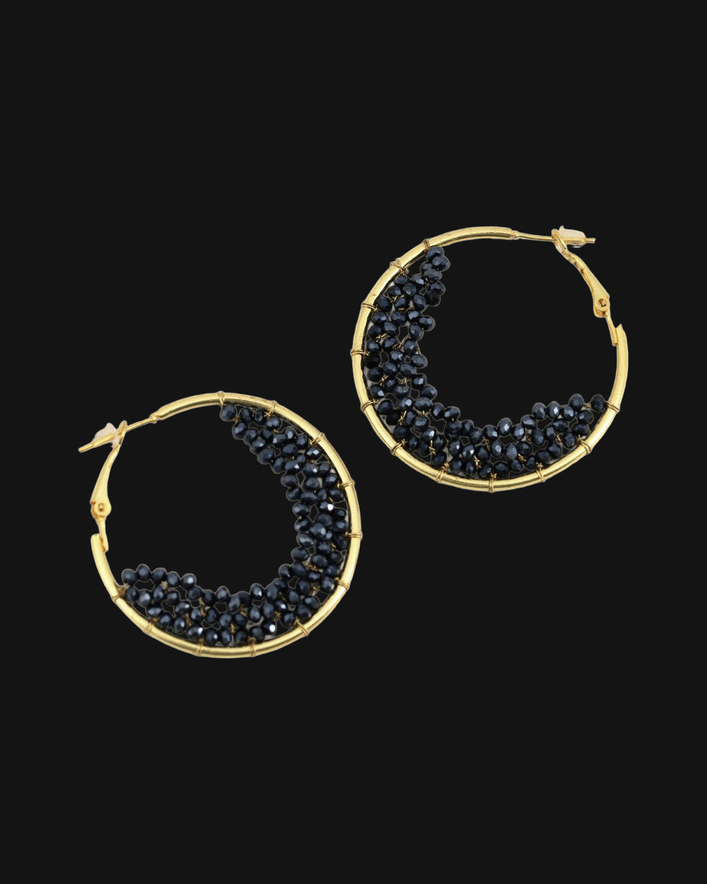 Gold-plated brass hoop earrings filled with a crescent of faceted black glass beads, hand-wrapped in India, shown on a black background