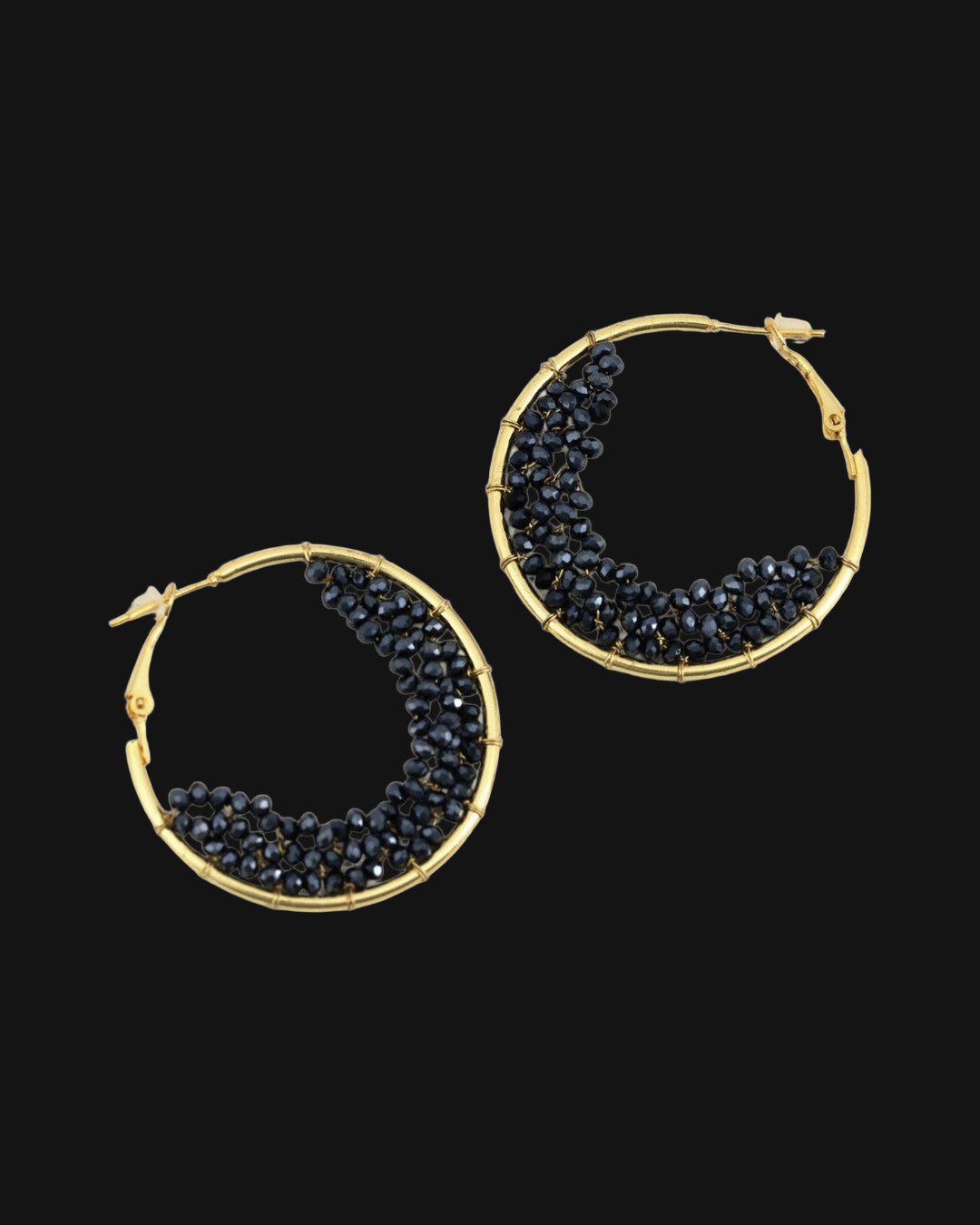 Gold-plated brass hoop earrings filled with a crescent of faceted black glass beads, hand-wrapped in India, shown on a black background