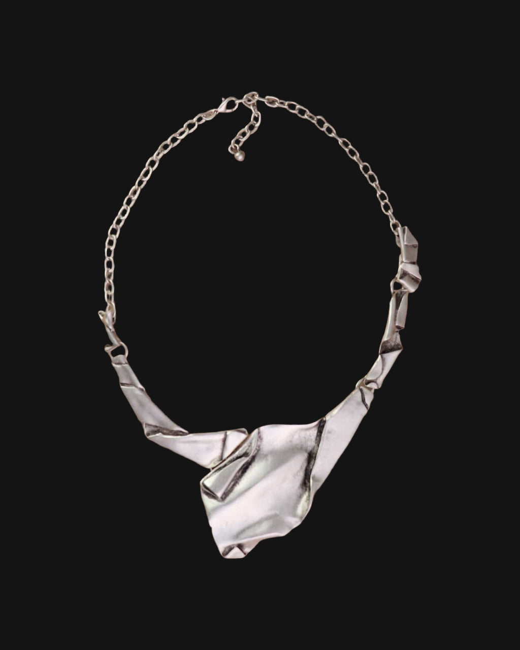 Full view of the crumpled-paper style silver-tone bib necklace with folded links and cable chain, shown on a black background