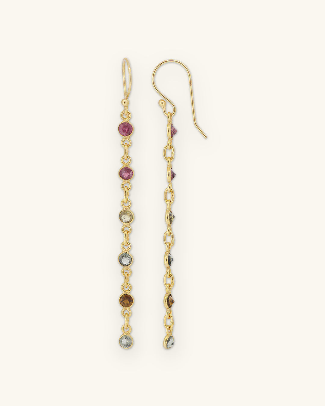 Six-stone tourmaline chain drop earrings with bezel-set stones on gold-plated brass, handmade in India, shown on a sand background