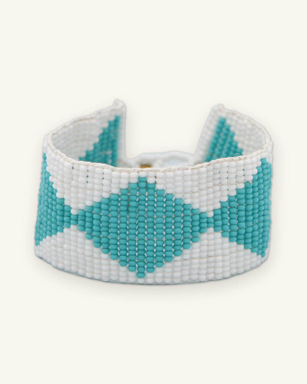 Diamond-motif loomed bead bracelet in Blue, turquoise diamonds on white Czech glass beads, shown on a sand background