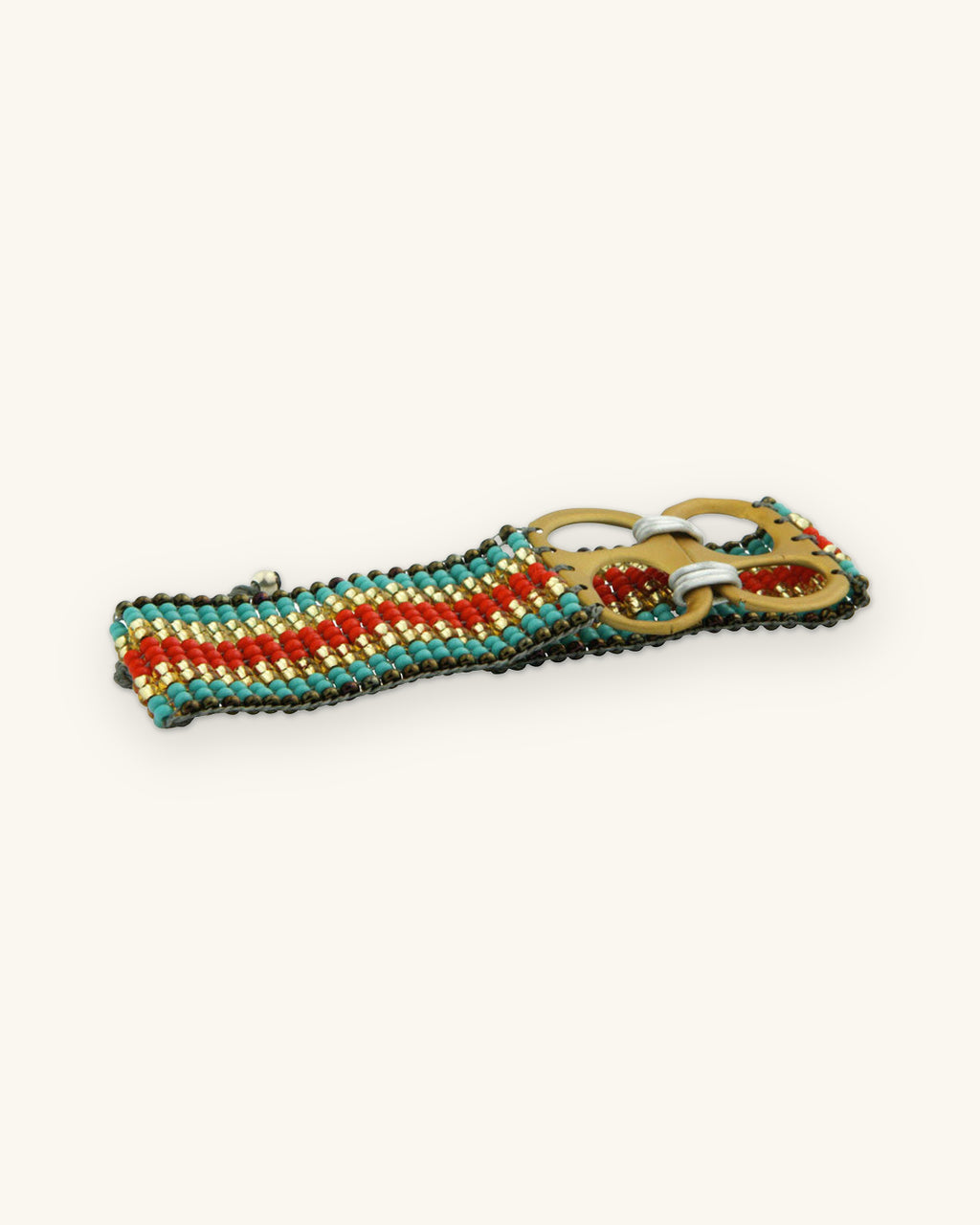 Turquoise, red and gold striped loomed glass bead bracelet with a double-tab closure, handmade in Colombia, shown on a sand background