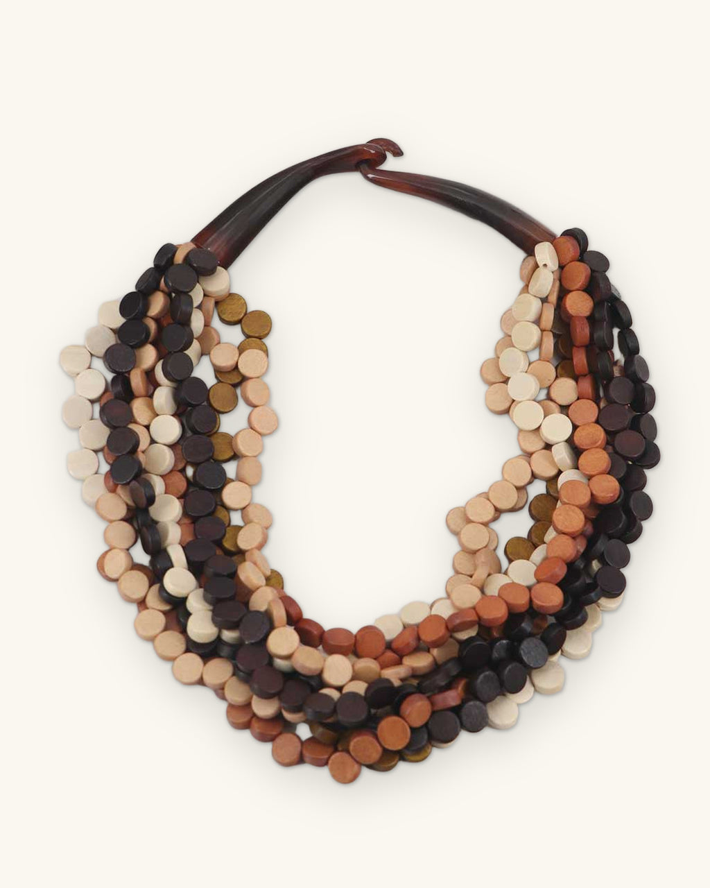 Multi-strand wood disc collar necklace in cream, rust and espresso with a curved horn clasp, handmade in the Philippines, shown on a sand background