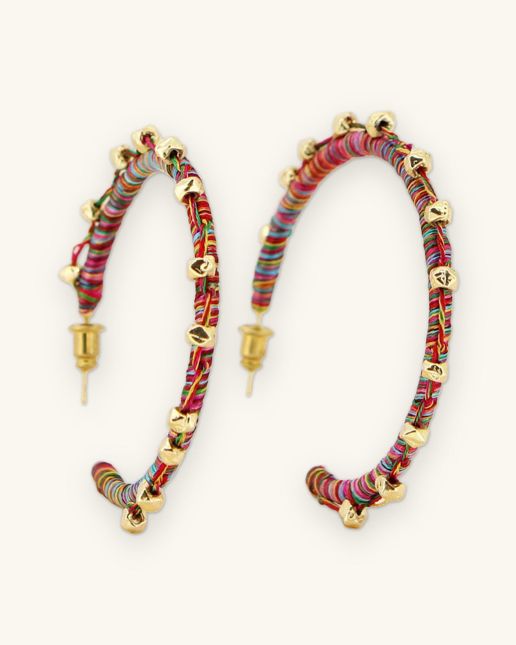 Multicolor thread-wrapped hoop earrings with gold-tone beads and post backs, hand thread-wrapped in India, shown on a sand background
