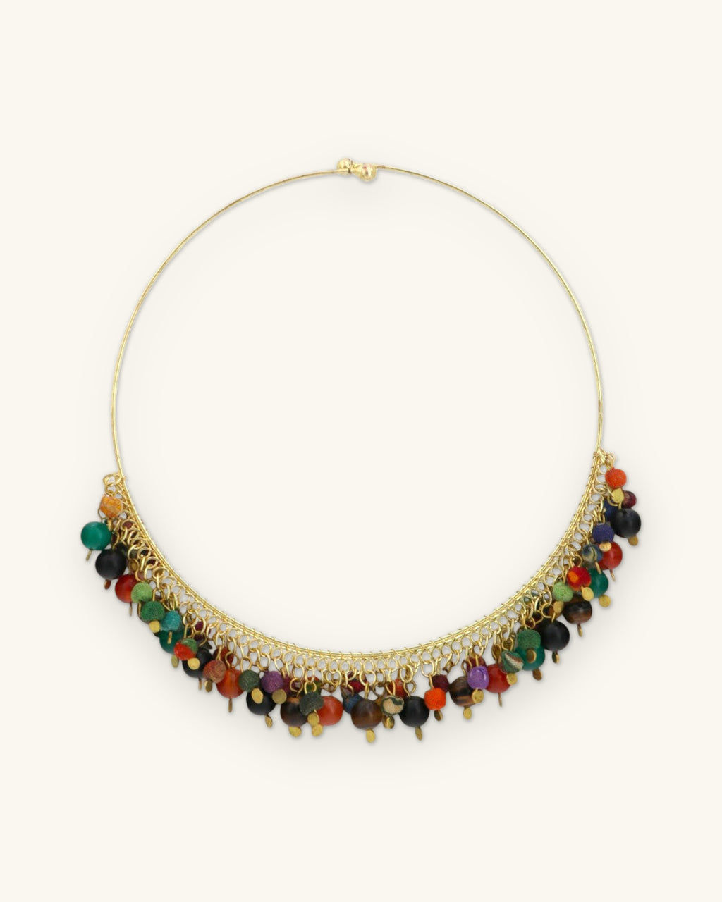 Full round of the gold-tone wire collar showing the hook closure and bead fringe along the front, shown on a sand background