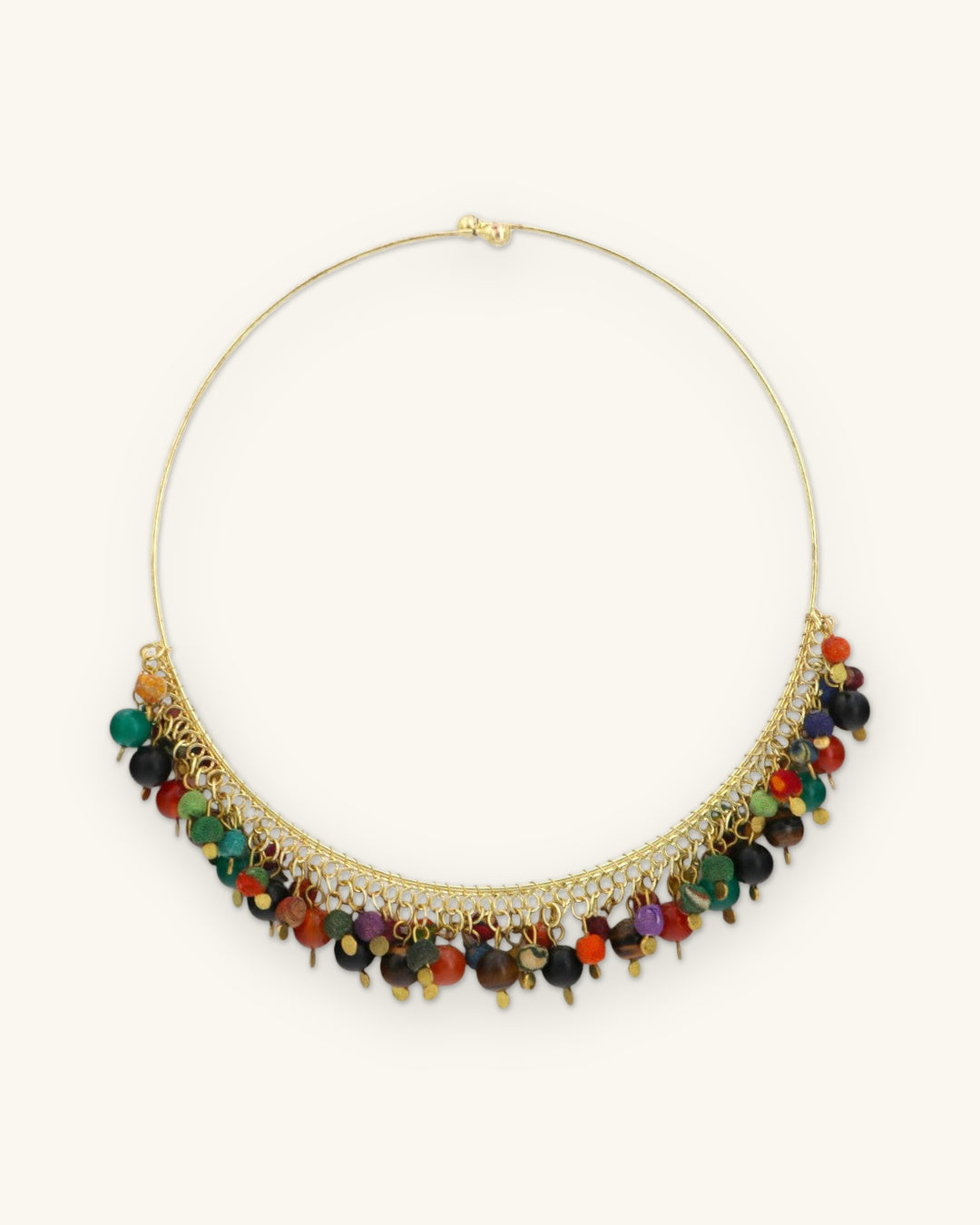 Full round of the gold-tone wire collar showing the hook closure and bead fringe along the front, shown on a sand background