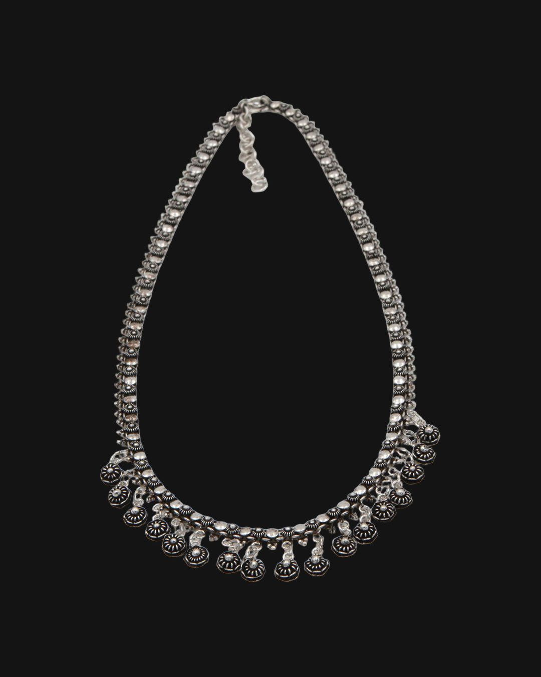 Hill tribe silver flower link necklace with a fringe of oxidized floret drops, hand-stamped in Laos, shown on a black background