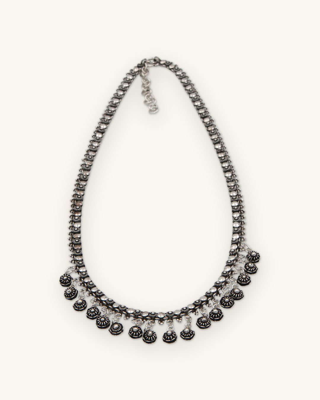 Hill tribe silver flower link necklace with a fringe of oxidized floret drops, hand-stamped in Laos, shown on a sand background