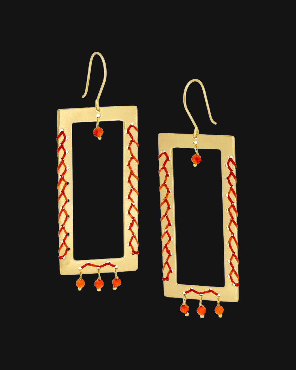 Brass rectangle frame drop earrings laced with orange thread and carnelian bead drops, handmade in India, shown on a black background