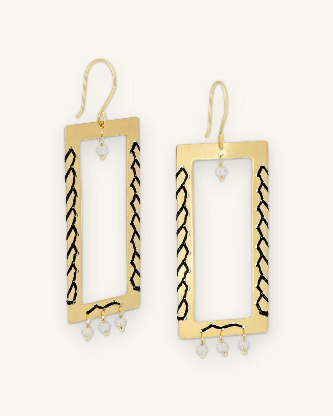 Brass rectangle drop earrings with black hand-laced thread and labradorite bead fringe, handmade in India, shown on a sand background