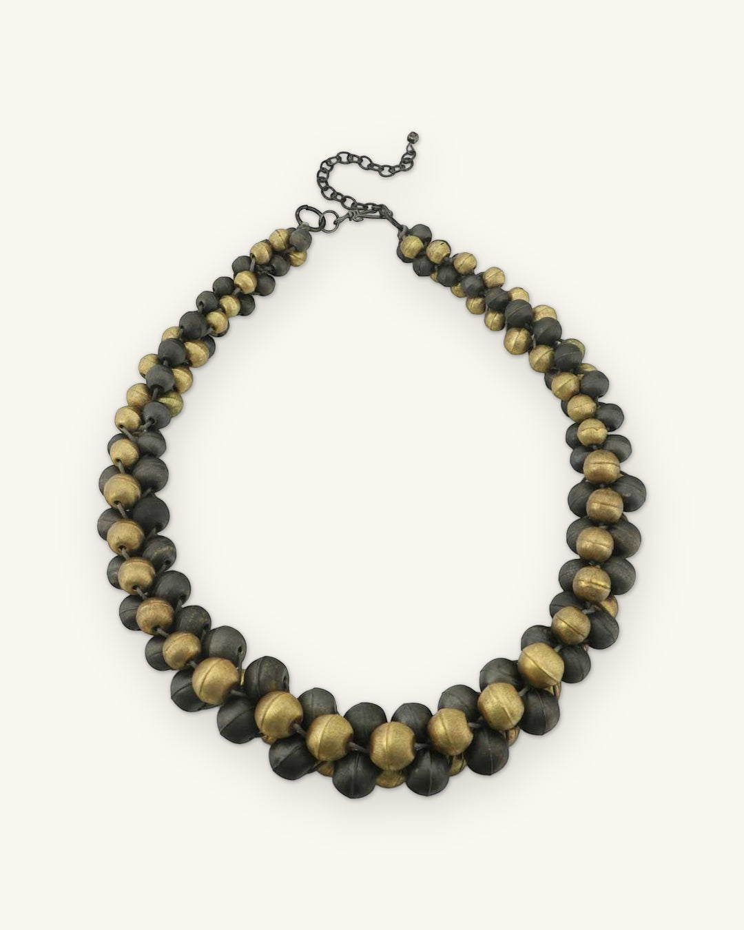 Full round of the antique gold and gunmetal bead collar with graduated beads at the front, shown on a sand background