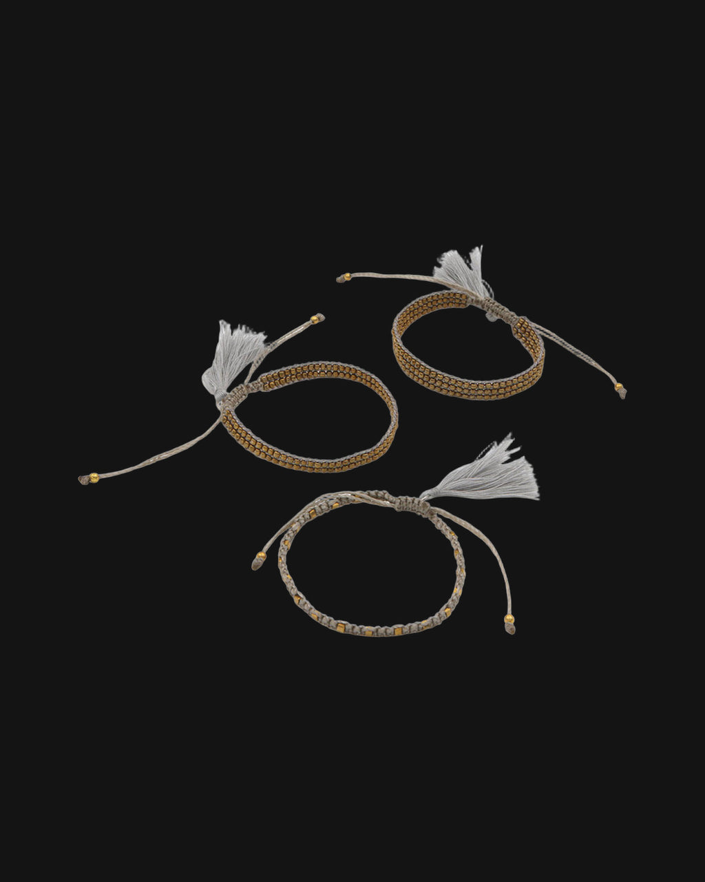Set of three beaded cord bracelets in Gray with gold-tone beads and adjustable tasseled ties, shown on a black background