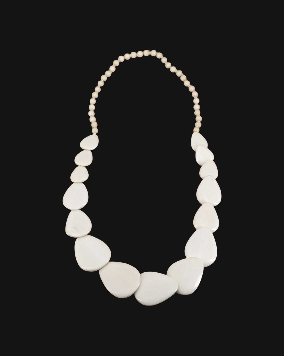 White guitar-pick shaped wood disc necklace on a round bead strand, laid flat, shown on a black background