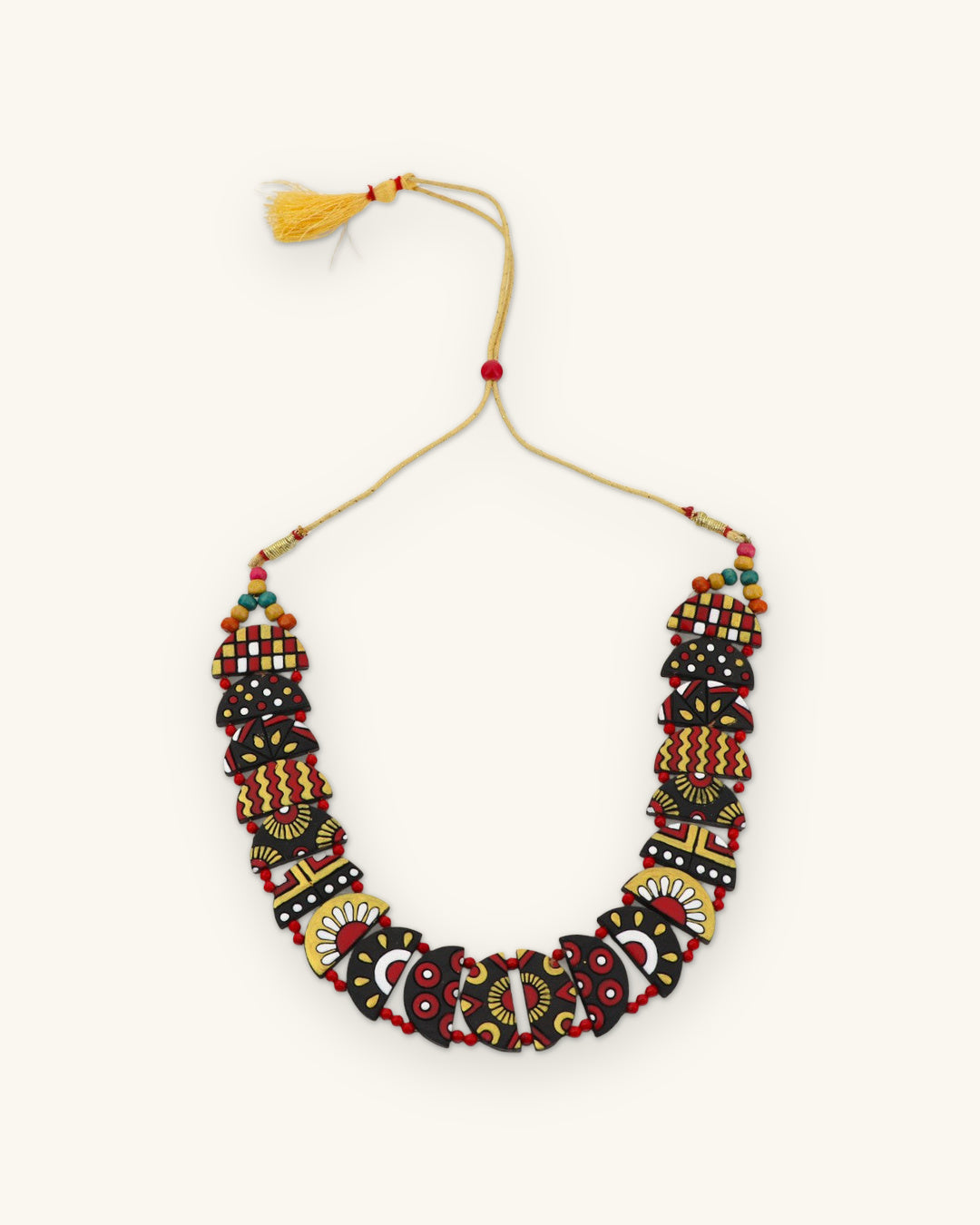 Full half-moon clay necklace laid flat, showing the adjustable cotton cord with a yellow tassel, shown on a sand background
