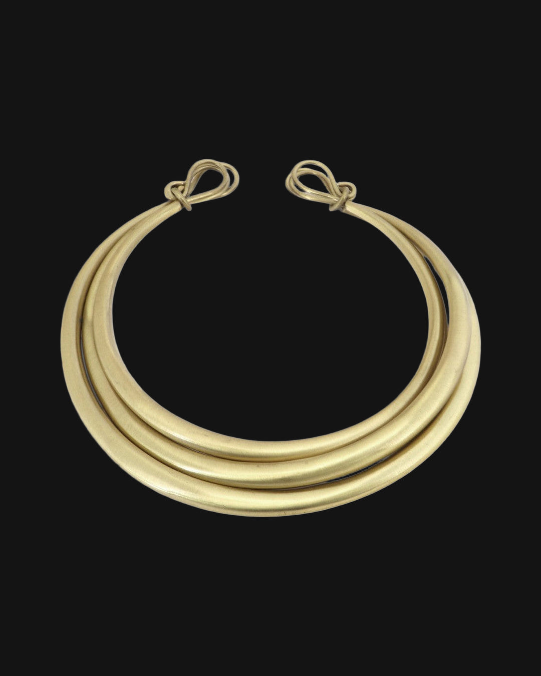 Front of the triple-strand brass collar showing the graduated bands and knotted wire ends, shown on a black background