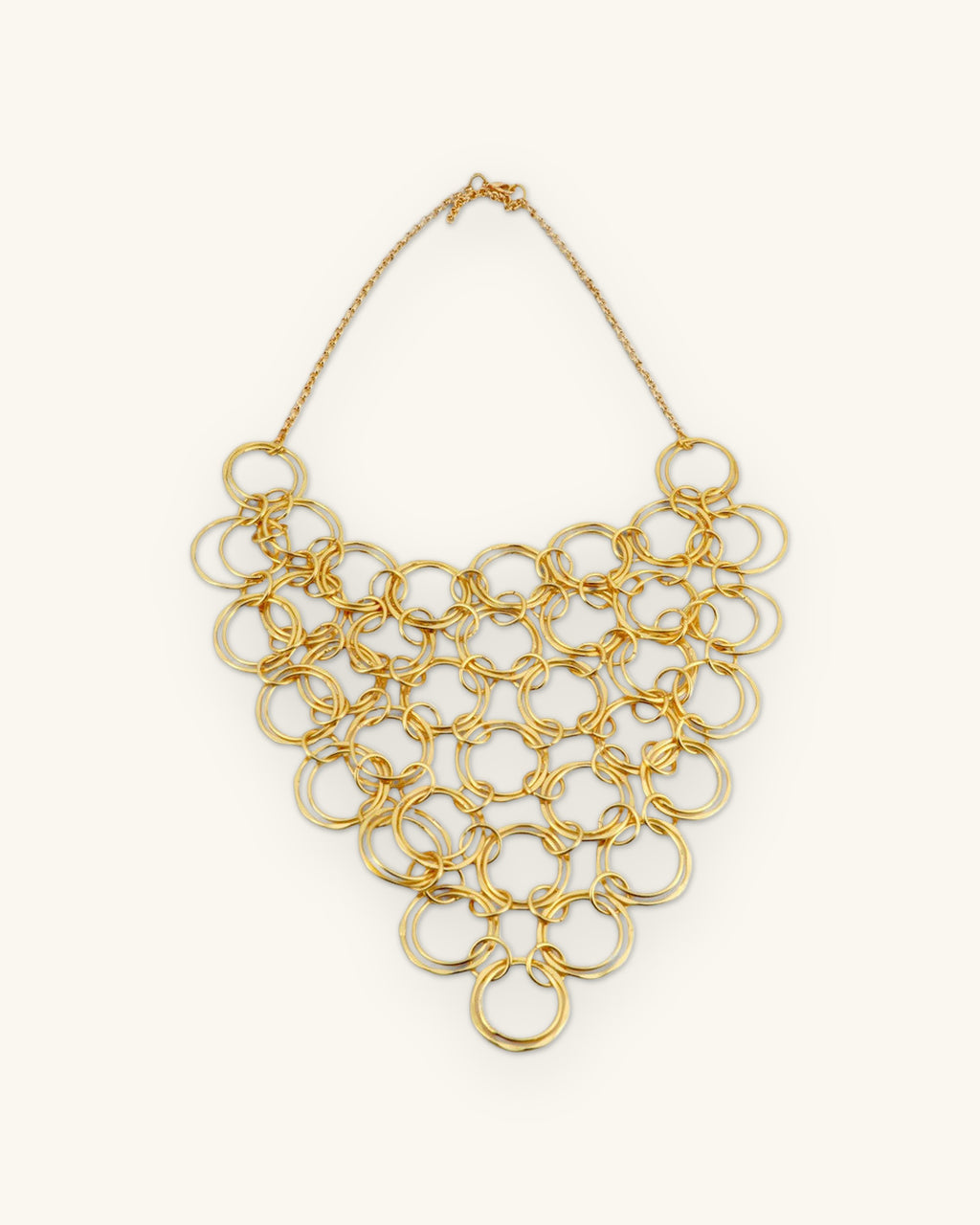 Full brass ring bib necklace laid flat, showing the fine chain and clasp, shown on a sand background