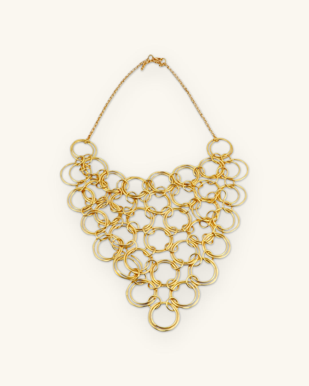 Full brass ring bib necklace laid flat, showing the fine chain and clasp, shown on a sand background