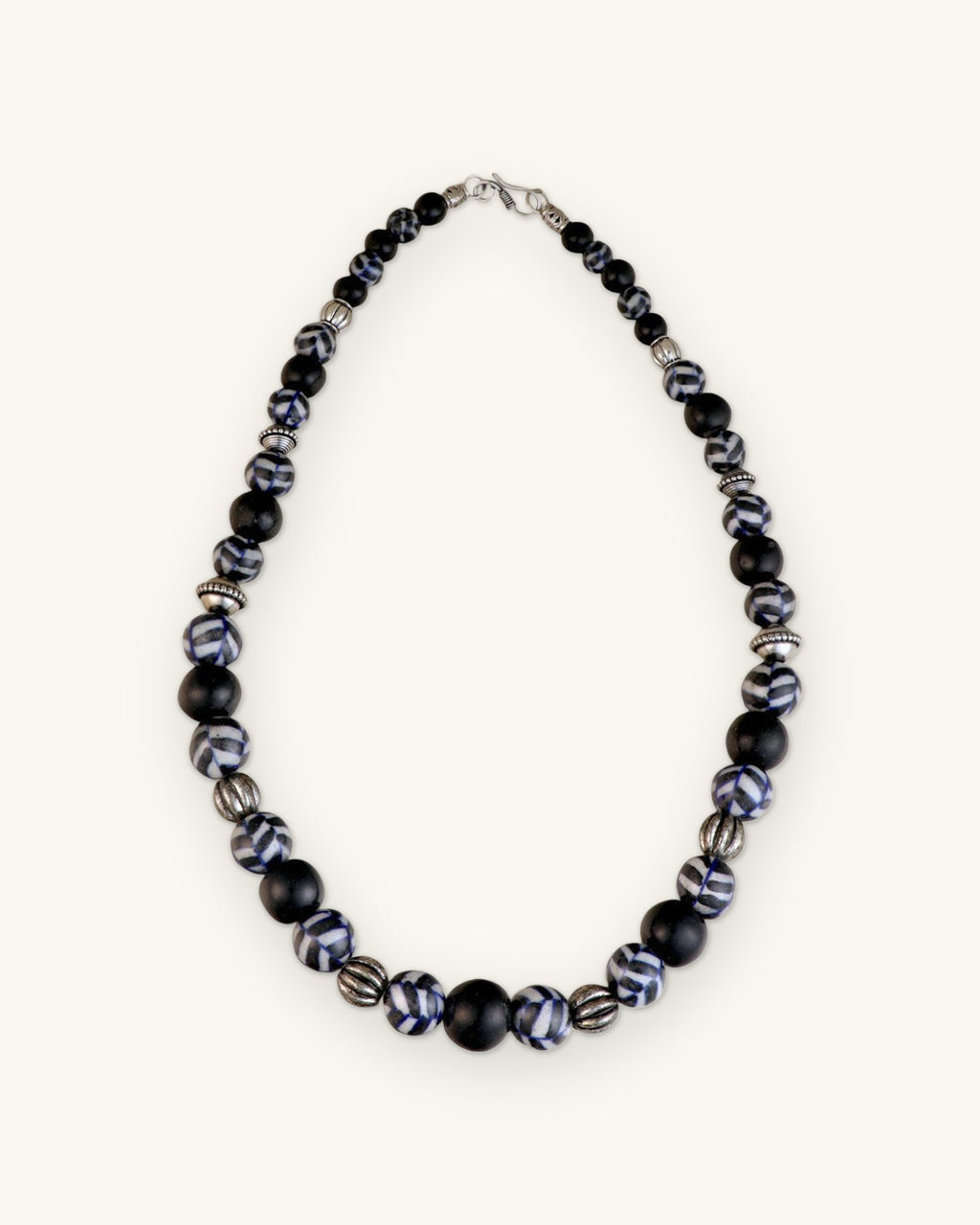 Full cobalt and black ceramic bead necklace laid flat with silver-tone lobster clasp, shown on a sand background