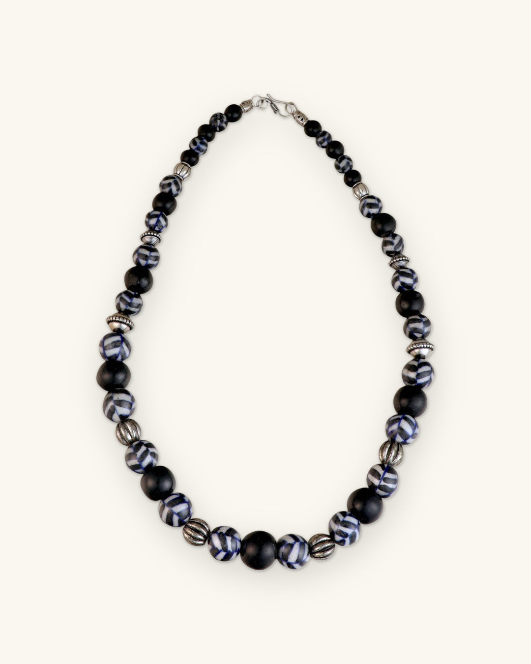 Full cobalt and black ceramic bead necklace laid flat with silver-tone lobster clasp, shown on a sand background