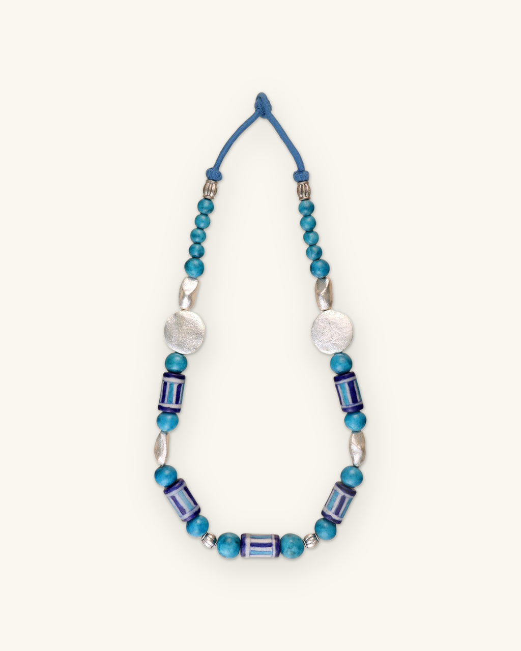 Full striped ceramic bead necklace laid flat, showing the blue cord loop closure, shown on a sand background