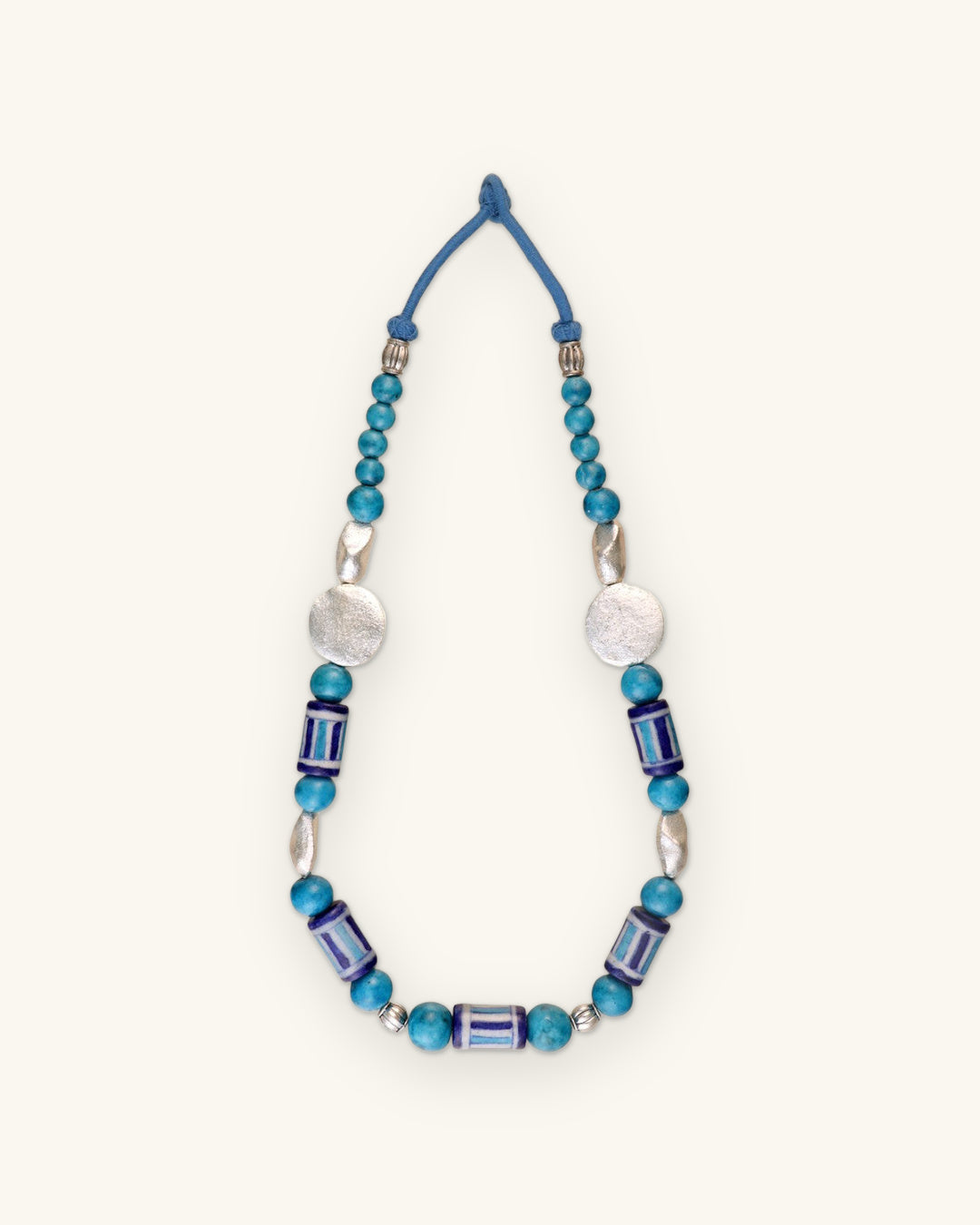 Full striped ceramic bead necklace laid flat, showing the blue cord loop closure, shown on a sand background