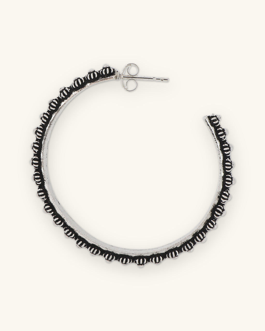 Pair of oxidized hill tribe silver floral hoop earrings set side by side, showing the post backs, shown on a sand background