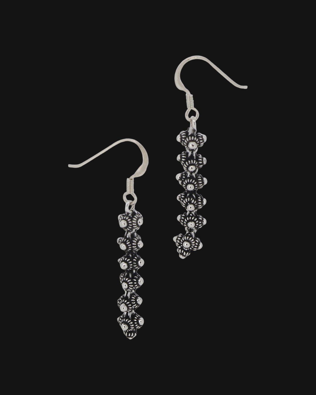 Stacked floret drop earrings in oxidized hill tribe silver on sterling fish-hook ear wires, handmade in Laos, shown on a black background