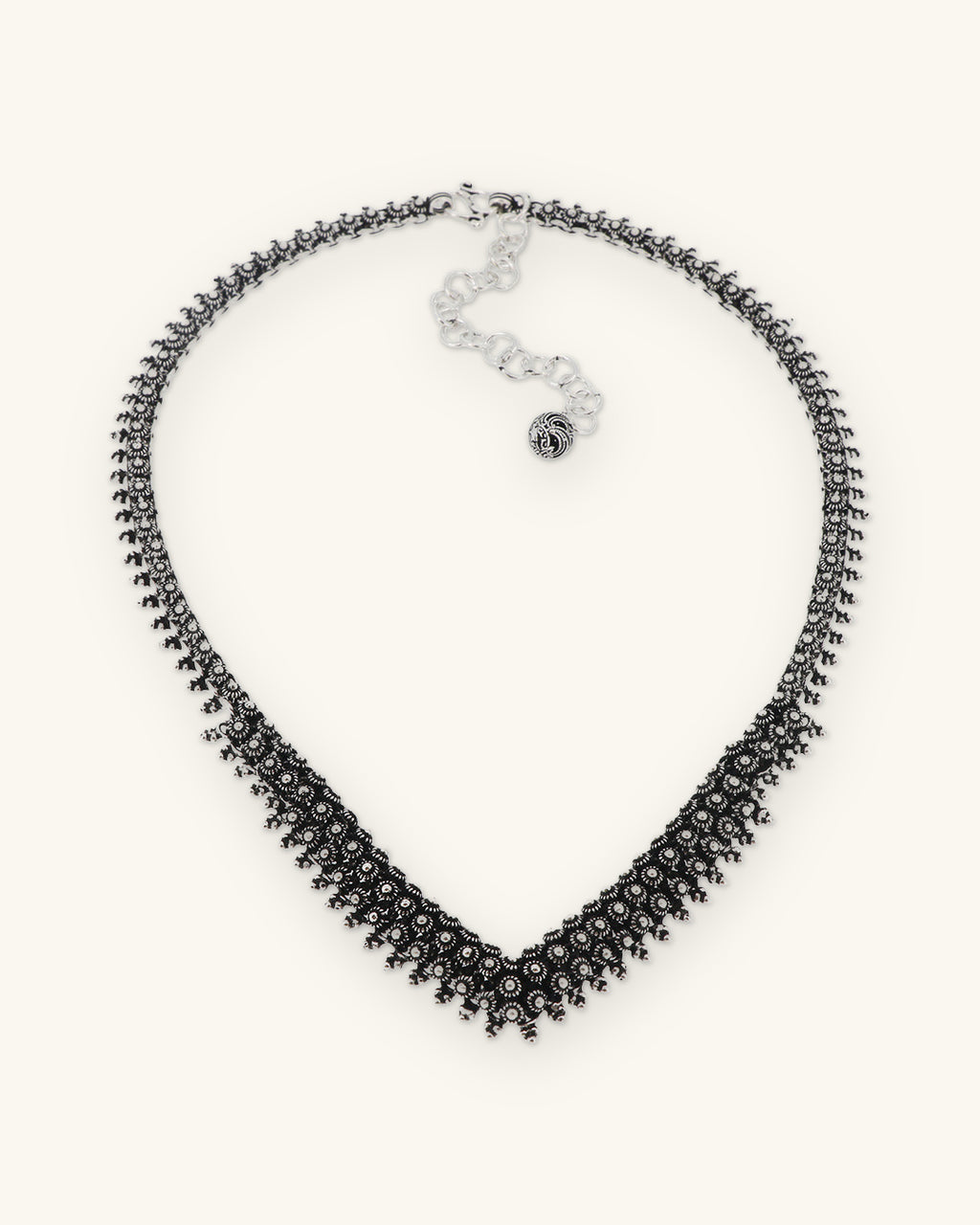 Hill tribe silver floret V-collar necklace with oxidized beaded texture and chain extender, Karen silversmithing from Laos, shown on a sand background