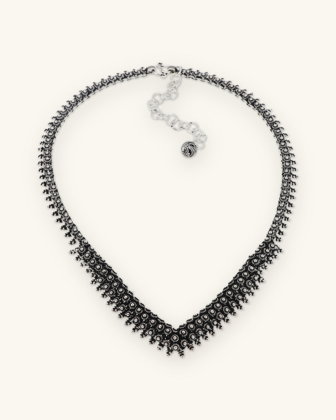 Hill tribe silver floret V-collar necklace with oxidized beaded texture and chain extender, Karen silversmithing from Laos, shown on a sand background