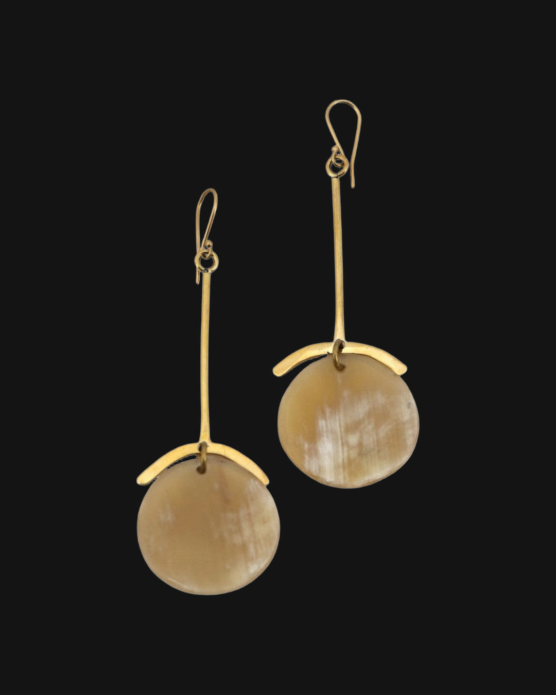 Long hammered brass bar earrings with honey-toned horn discs and curved brass caps, handmade in Kenya, shown on a black background