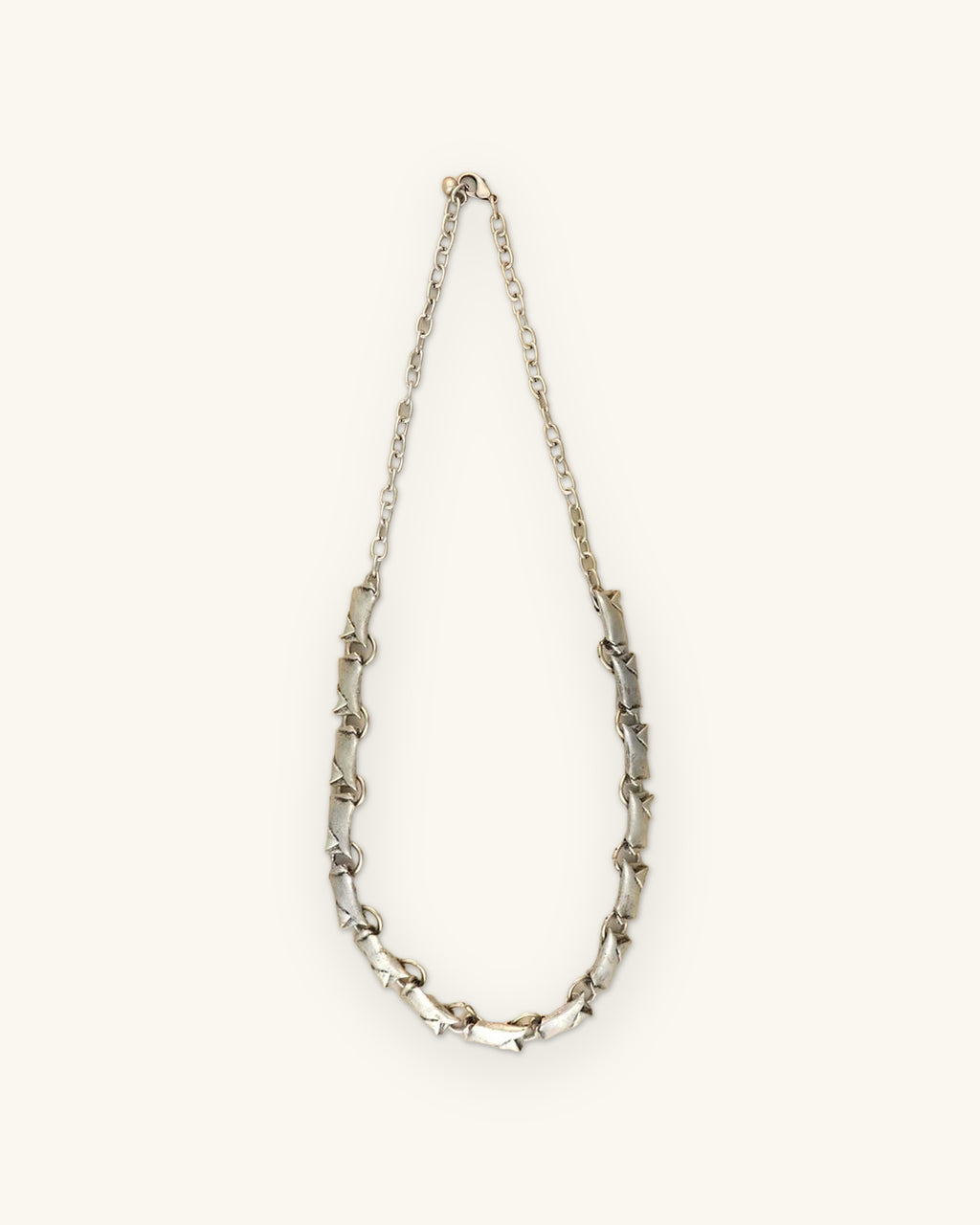 Full length of the silver-tone bar link necklace with a fine chain back and lobster clasp, shown on a sand background