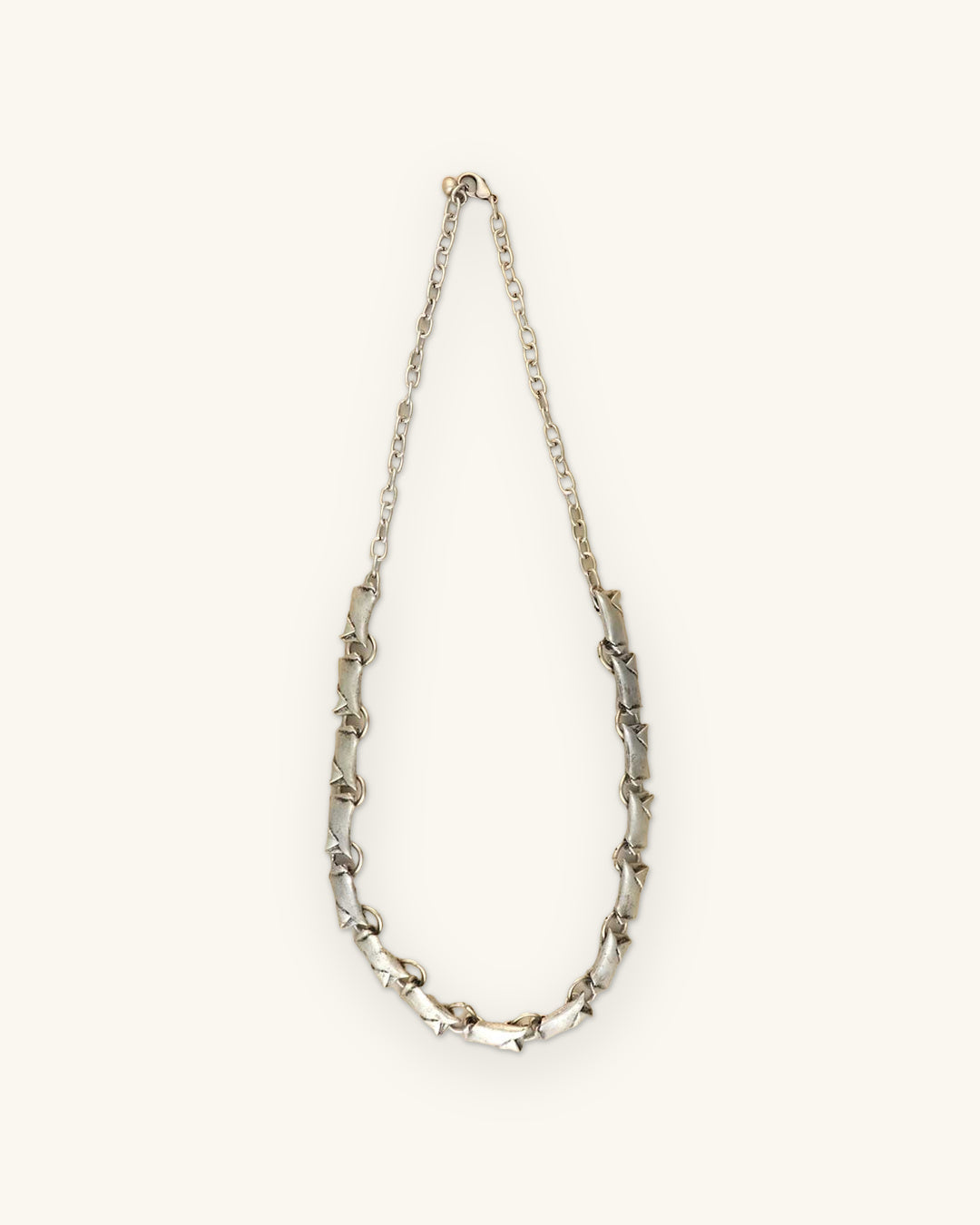 Full length of the silver-tone bar link necklace with a fine chain back and lobster clasp, shown on a sand background