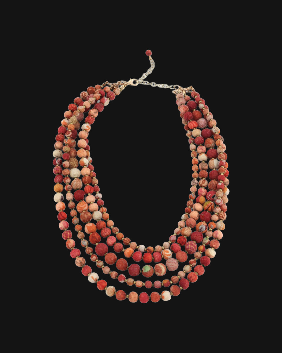 Sunset-toned five-strand fabric bead necklace laid flat with its chain extender and red bead drop, shown on a black background