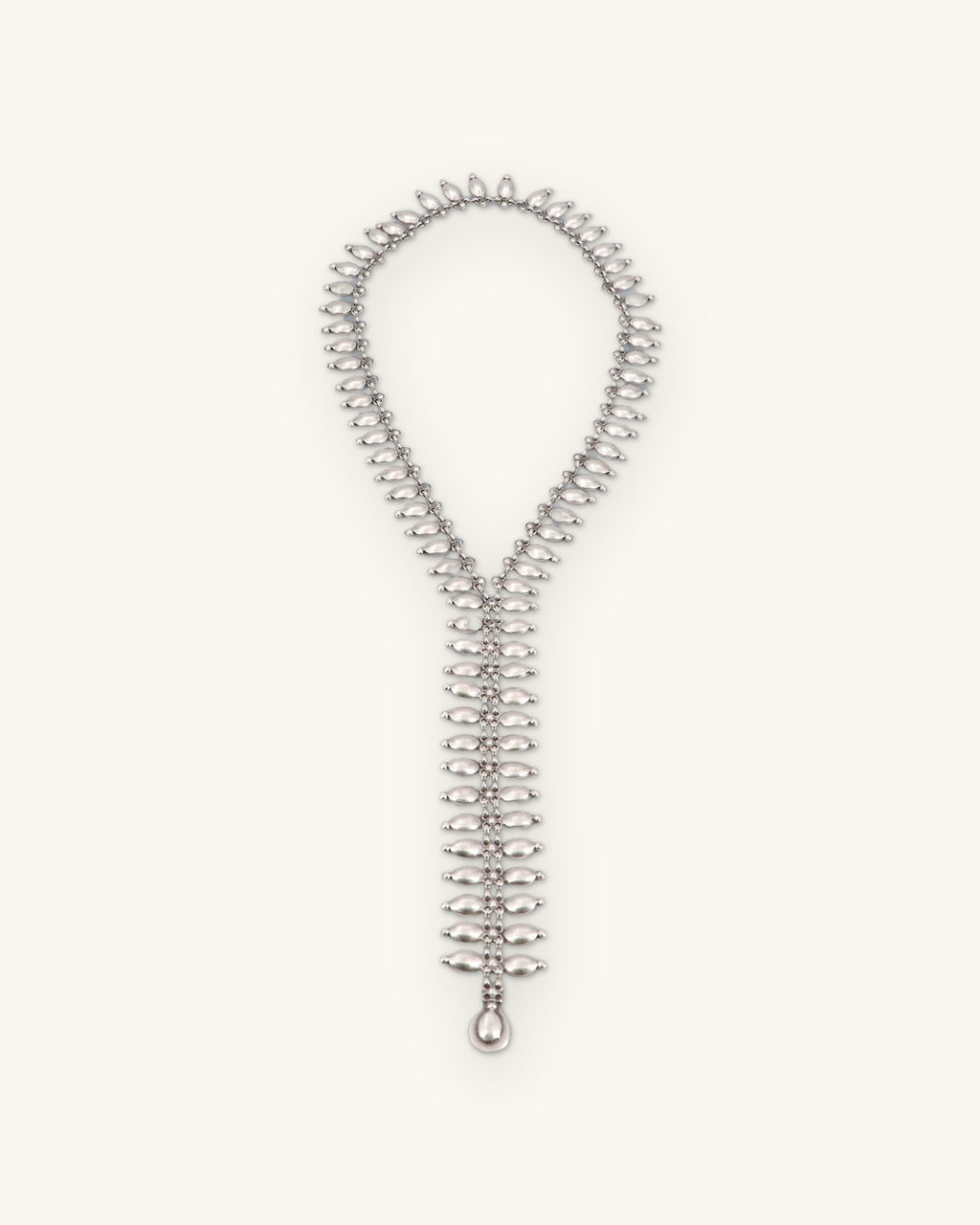 Full length of the antiqued silver-tone fringe lariat necklace laid flat, ending in a teardrop, shown on a sand background