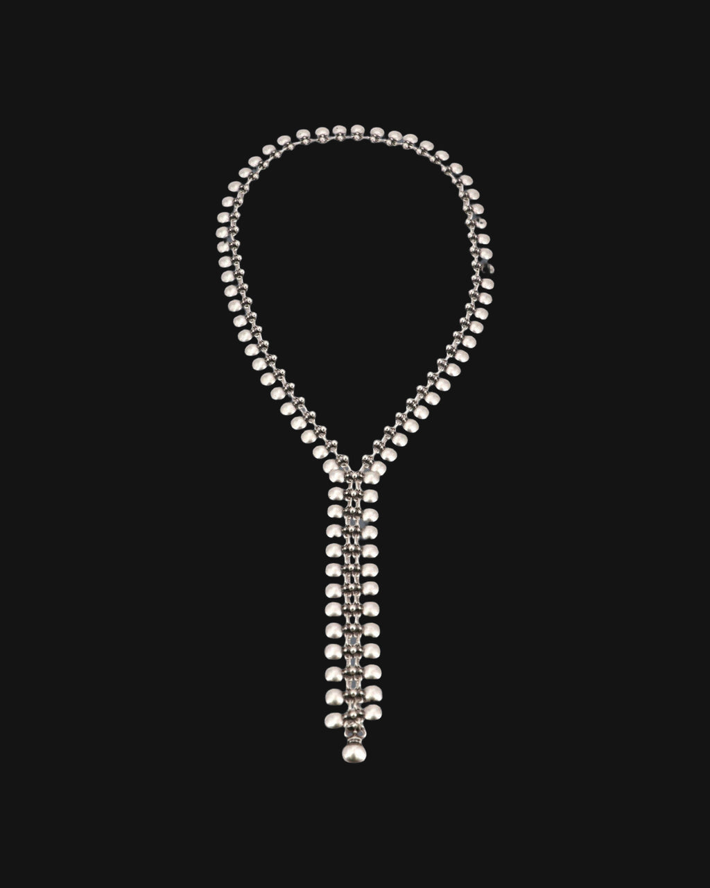 Full loop of the silver-tone bead-link lariat necklace laid flat with its narrow woven drop, shown on a black background