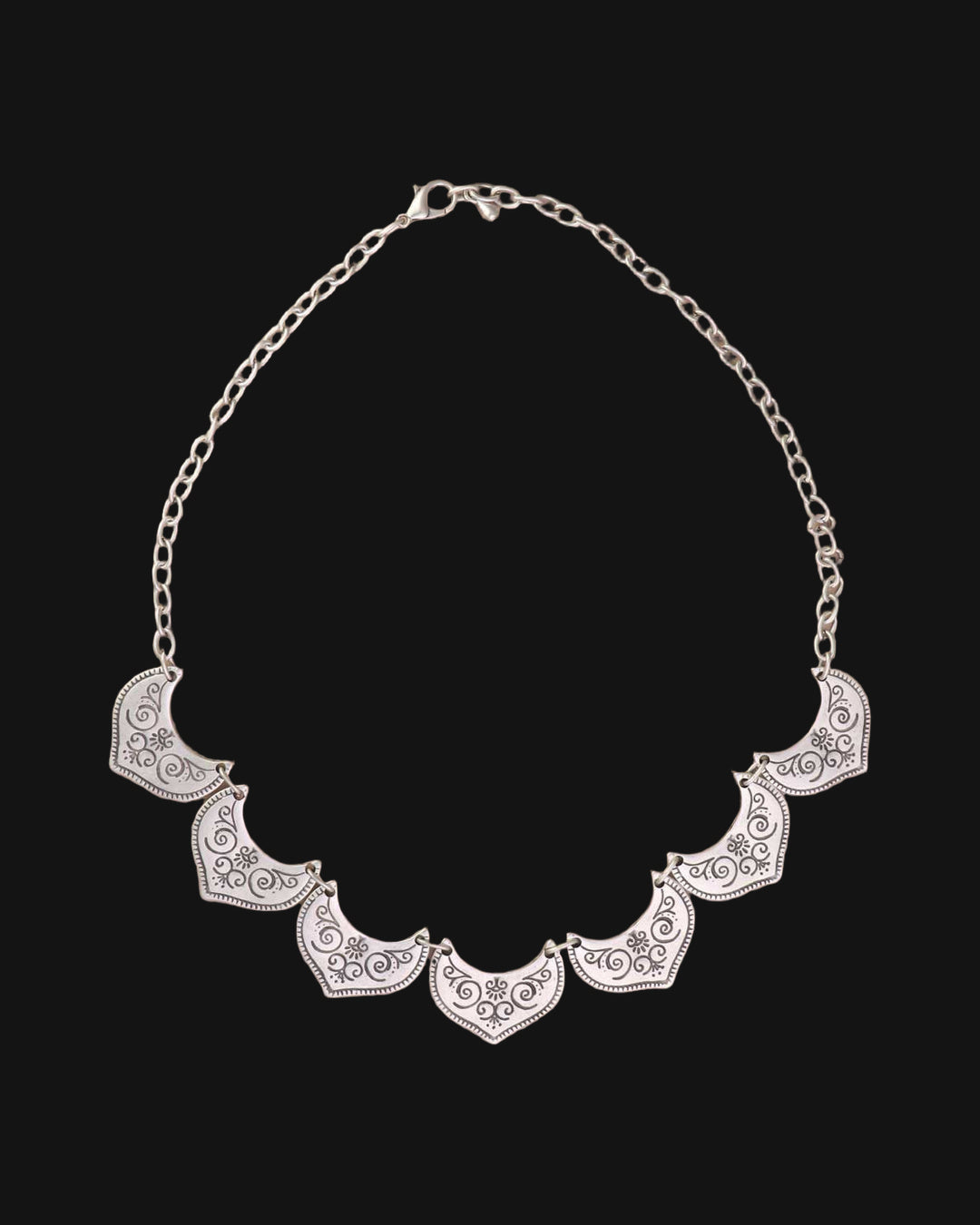 Silver-tone fan-plate bib necklace laid flat with its link chain and lobster clasp, shown on a black background