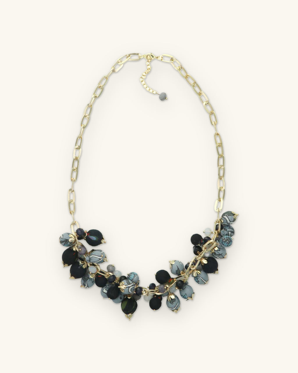 Full length of the clustered fabric bead necklace on a gold-plated brass paperclip chain, shown on a sand background